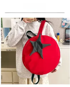 Detail of red tomato shaped backpack showing waterproof fabric and green star leaf stem