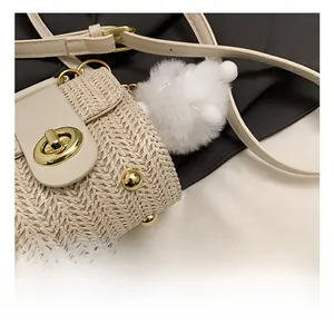 Close-up of woven texture on cream crossbody bag with gold hardware and plush charm