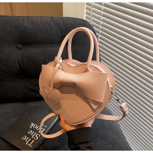 Détail du sac à main rose en forme de cœur avec nœud 3D et pendentif cœur élégant