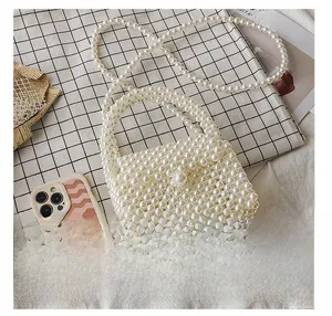 Detailed size comparison of handmade pearl beaded mini handbag next to a smartphone