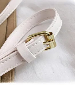Detail of light pink leather shoulder strap with polished gold-tone metal buckle
