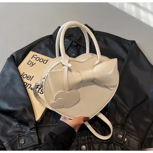 Detail of white heart-shaped bag with bow and pendant on black leather jacket