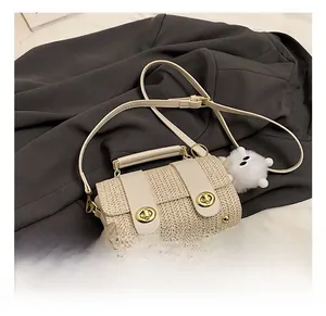 Detail of woven straw shoulder bag with leather flap, gold lock and plush charm