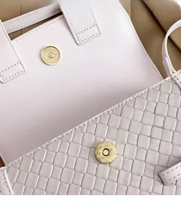 Close-up of woven leather saddle bag featuring a round golden metallic magnetic buckle