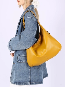 Détail d'un sac cabas en cuir grainé jaune gingembre porté avec une veste en jean