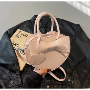 Detailed view of a light pink heart-shaped bag with a large bow and dual handles
