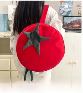 Close-up of a red tomato-shaped backpack with green star leaves on a person's back