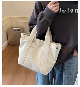 Detail view of cream canvas tote bag with front pocket and durable woven handle