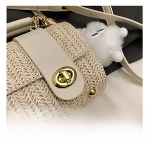 Macro shot of off-white straw weave texture with light gold metal turn-lock and fur ball charm