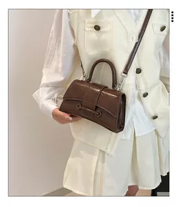 Glossy brown hourglass handbag with top handle and shoulder strap shown on a model