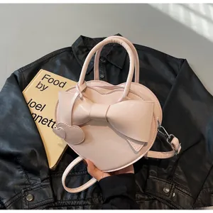 Detailed view of heart-shaped crossbody bag featuring a large bow and leather charm