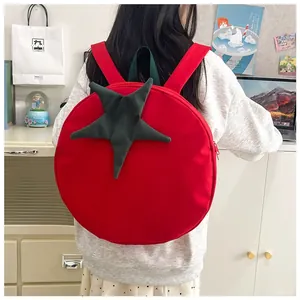 Detail of cute red tomato backpack featuring green stem handle and adjustable straps