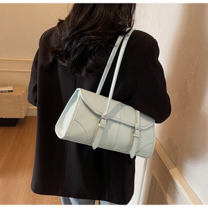 Rear view of mint green underarm bag with double straps on a black blazer model