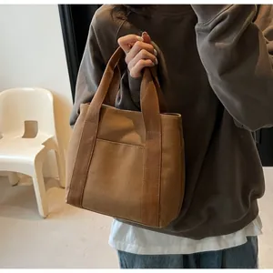 Close-up of caramel canvas tote bag showing the front pocket and reinforced handles