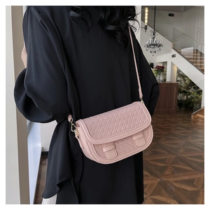 Detailed view of pink woven texture saddle bag with golden metal ring and thin shoulder strap