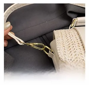 Detailed close-up of golden metal hooks and woven texture on a beige summer beach bag