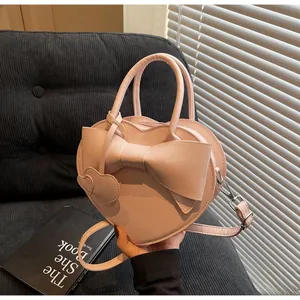 Detailed view of a pink heart-shaped bag with a large bow and dual heart charms