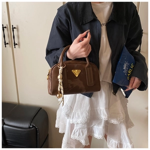 Détail d'un sac Boston marron avec logo triangle doré et ruban rayé élégant