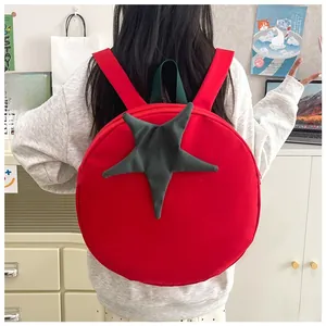 Close-up of creative red tomato shaped backpack with green leaf detail and wide strap