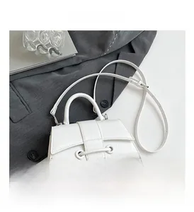 Detail shot of white hourglass handbag with cracked texture and top handle on gray suit