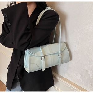 Detail of mint blue rectangular underarm bag with parallel buckle straps on matte leather