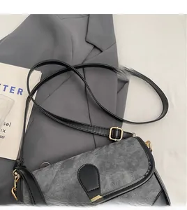 Détail de la bandoulière en cuir noir et boucles dorées sur sac en velours gris