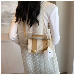 Detail of woven straw bucket bag featuring brown leather trim and cute furry charm