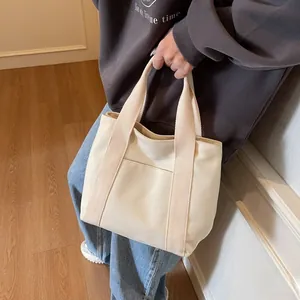 Detail of cream canvas tote bag showing the external pocket and wide webbing handles