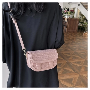Pink saddle crossbody bag featuring a fine woven texture and adjustable shoulder strap