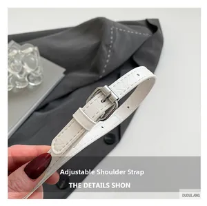 Close-up of adjustable white croc-embossed leather shoulder strap with silver buckle