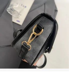 Détail de la quincaillerie dorée claire et texture denim gris avec bord en cuir noir
