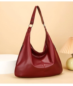 Gros plan d'un sac hobo en cuir rouge avec anneaux métalliques et texture premium