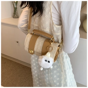 Detail of a cylindrical straw bag with a plush charm accessory worn by a model