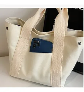 Detail of canvas tote bag featuring a practical front pocket and durable metal side snaps