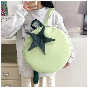 Detail shot of a light green round backpack with a dark green star on a female model