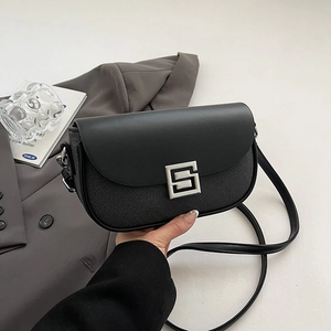 Minimalist black square saddle bag with leather patchwork and silver buckle on a blazer