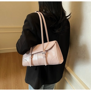 Pink rectangular leather shoulder bag with silver buckle straps worn by a model in a blazer