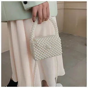 Detail view of handmade beaded pearl crossbody bag held by a model in green blazer