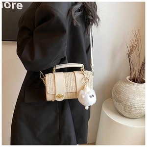 Close-up of woven straw handbag with gold twist lock and a cute plush doll charm detail