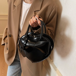Sac à main élégant noir en forme de cœur avec grand nœud porté par un mannequin