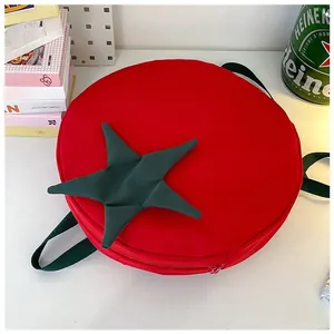 Top view of red tomato-shaped backpack with green leaf detail and adjustable straps