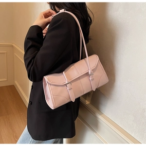 Detail view of the pale pink leather underarm bag with decorative dual buckle straps