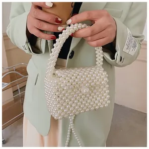 Detail of handmade cream pearl woven handbag with delicate bead texture and top handle