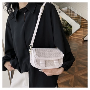 Detail of cream-white woven saddle bag with adjustable straps on a female model