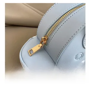 Detail of smooth gold zipper and neat stitching on light blue leather cartoon handbag