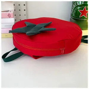 Close-up of creative red tomato shaped backpack with green leaf details and durable zipper