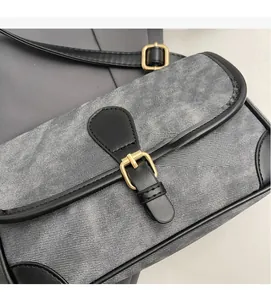 Gros plan d'un sac bandoulière contrasté en sergé gris avec boucle métallique dorée chic