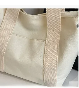 Close-up of cream white canvas tote bag showing thick woven texture and front pocket detail