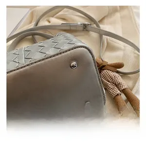 Detail of woven leather bucket bag base with protective metal feet and a teddy bear charm