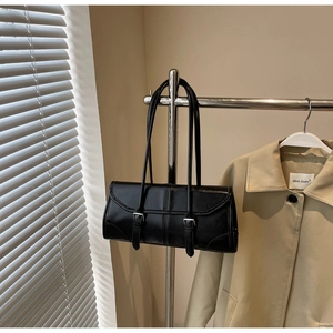 Detail of black rectangular shoulder bag with dual straps and metallic buckle accents